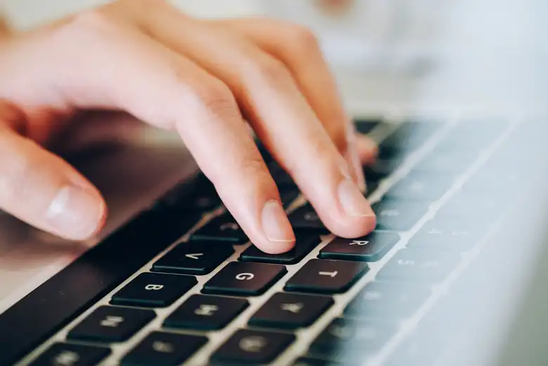 Mano escribiendo en teclado de laptop