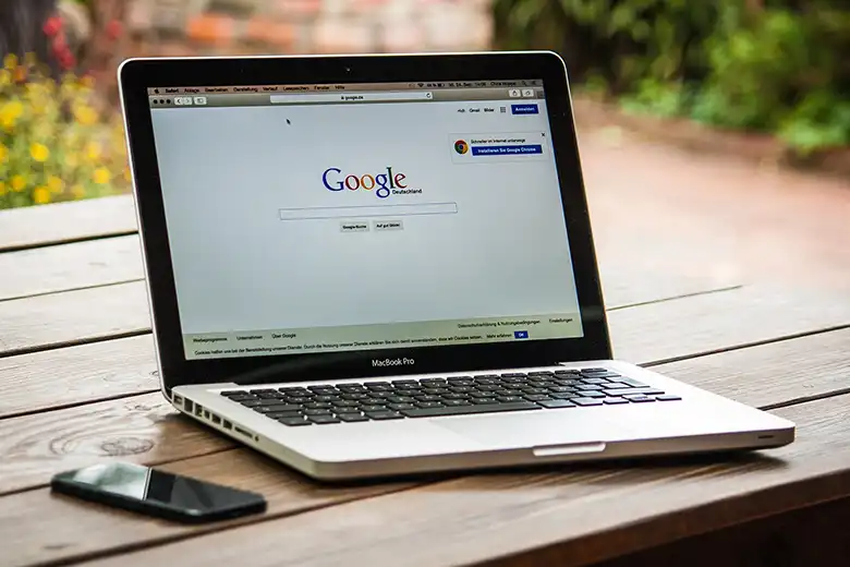 Laptop sobre mesa mostrando página principal de Google